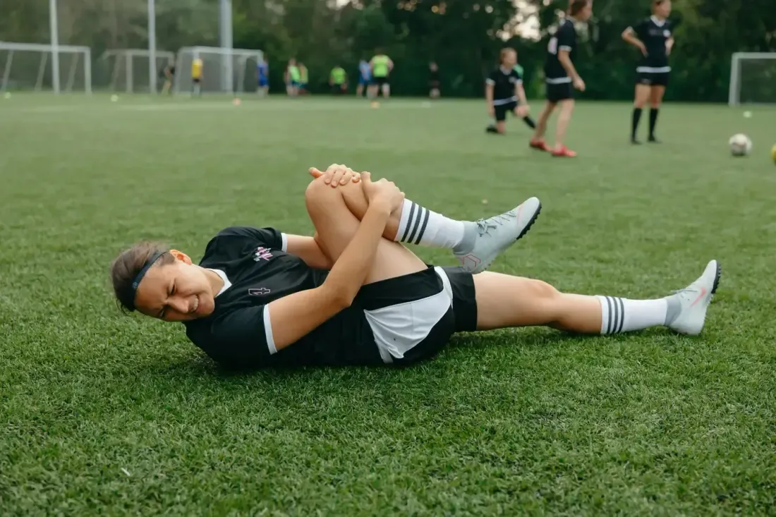 A soccer player down on the pitch holding their knee