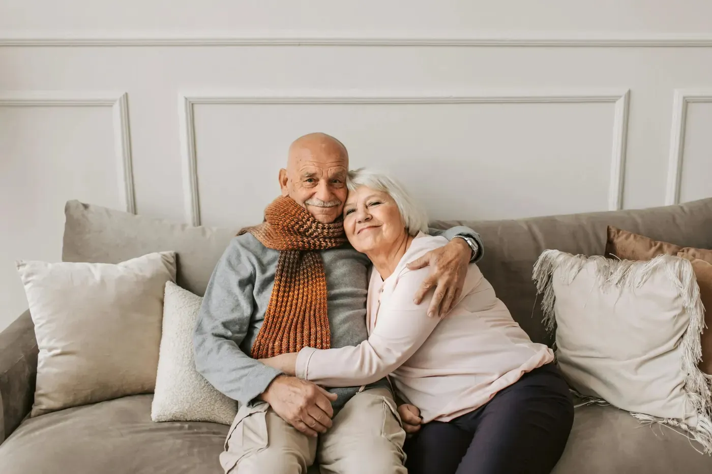 An older couple settled comfortably on their sofa at home