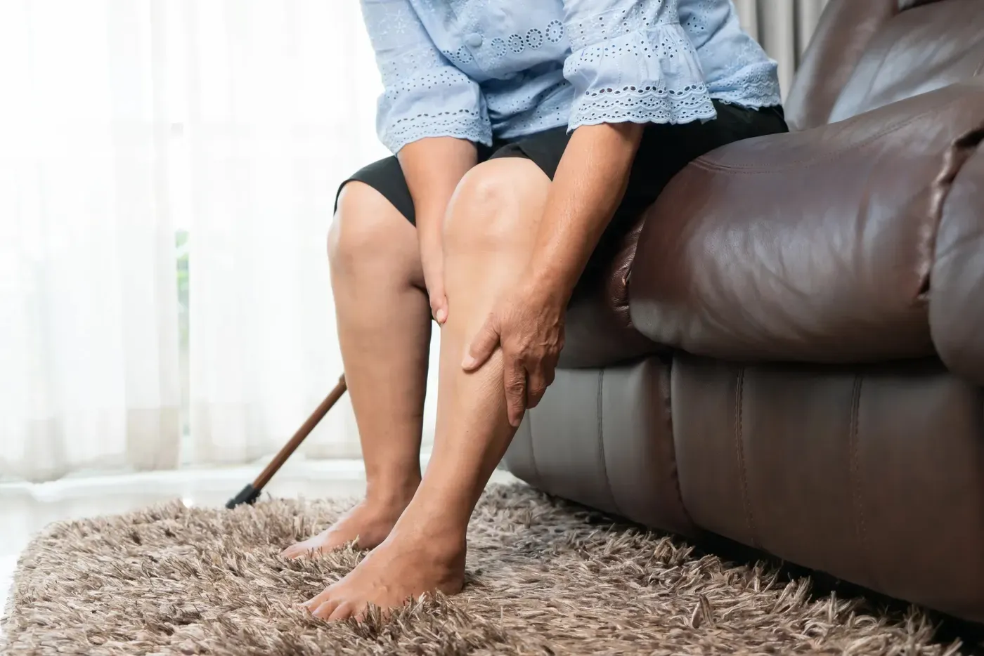 An older woman on a sofa checking a swollen leg